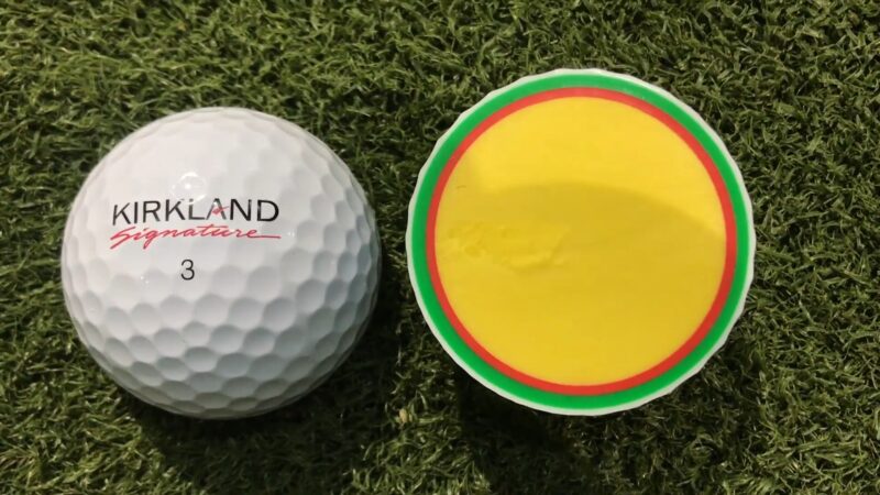 Kirkland golf ball next to a cross-section showing its multi-layer core structure on turf