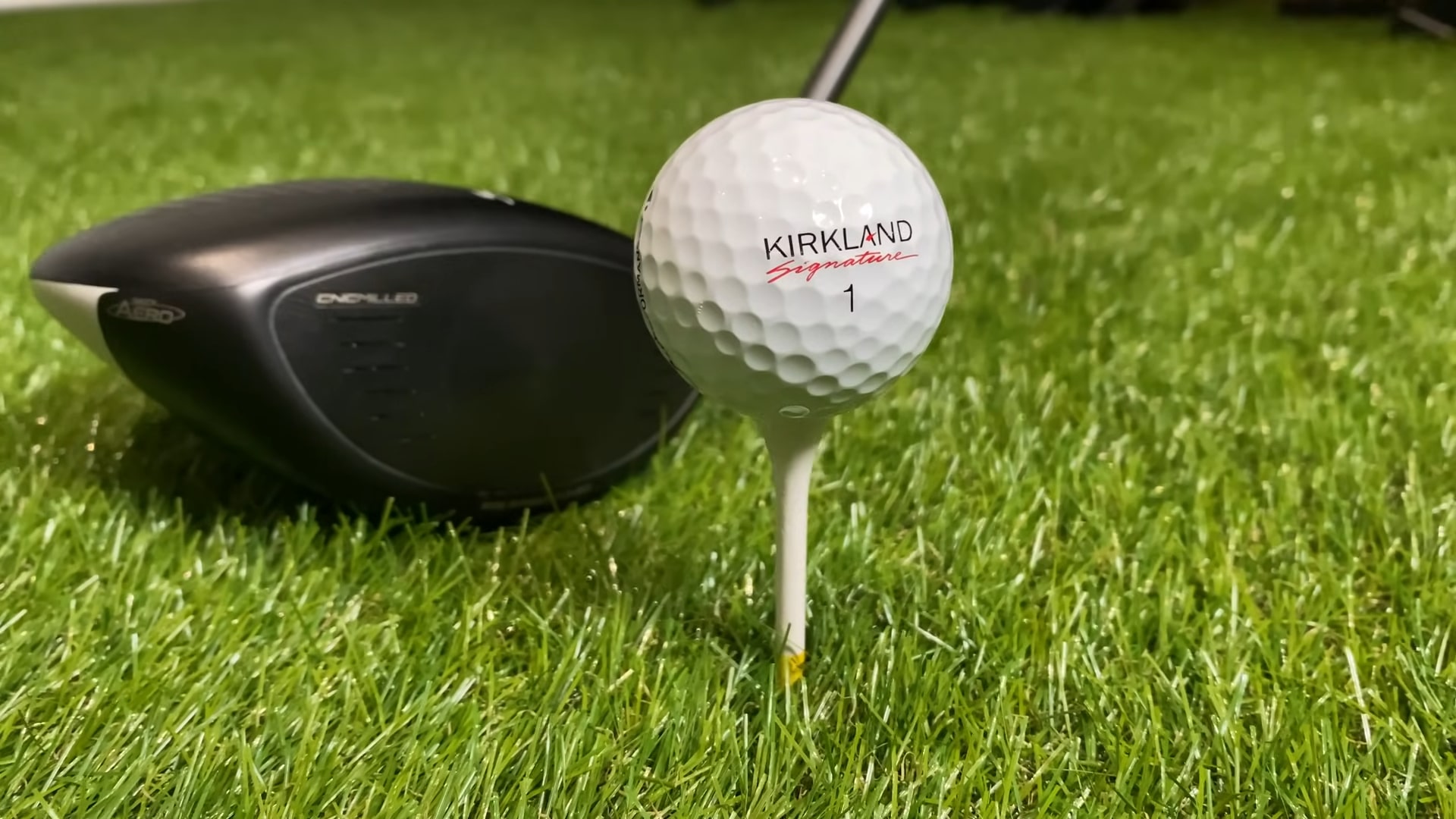 Kirkland Signature golf ball teed up on grass with a driver club in the background
