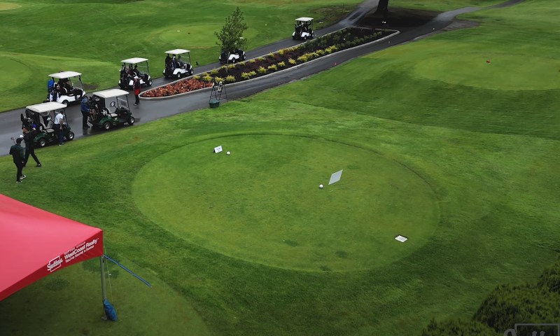 Aerial view of a golf course tee box area featuring several parked golf carts